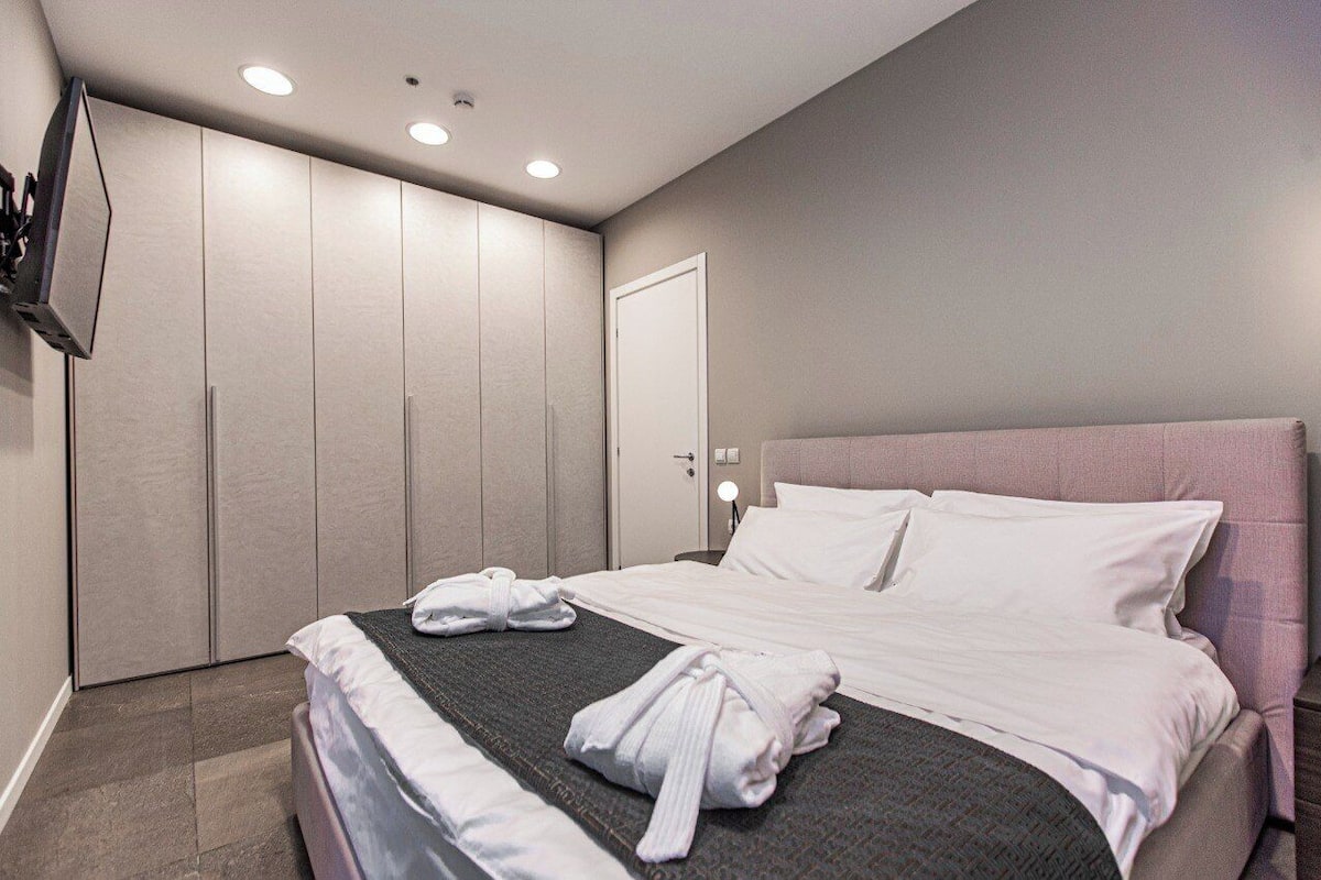 Une chambre d’hôtel moderne équipée d’un grand lit, d’une armoire, d’un téléviseur à écran plat et d’une porte.