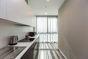 A modern kitchen with a stainless steel kettle, a stove, and a microwave. - Abylai Khan Plaza Premium Apartments (Almaty)
