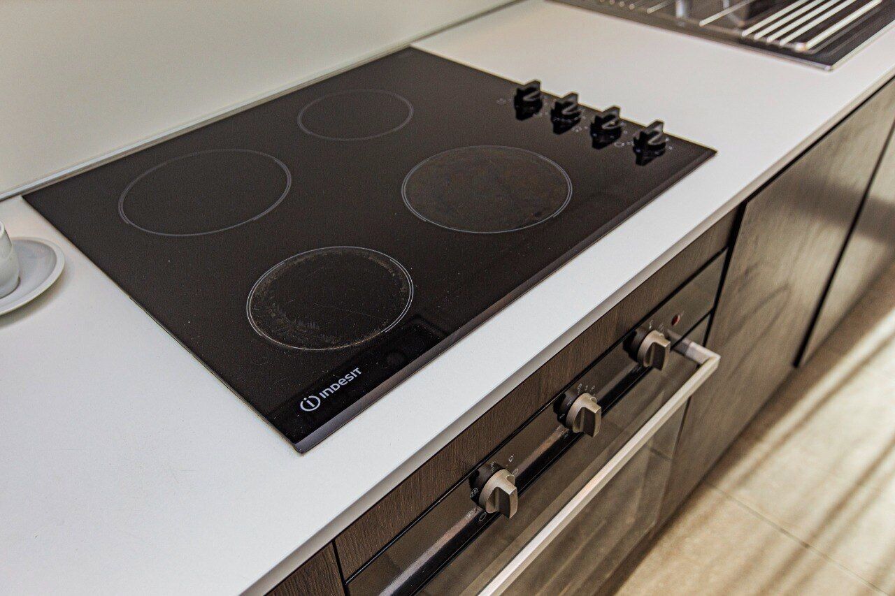Una cucina con piano cottura a induzione, un piano di lavoro bianco e un forno in acciaio inossidabile.