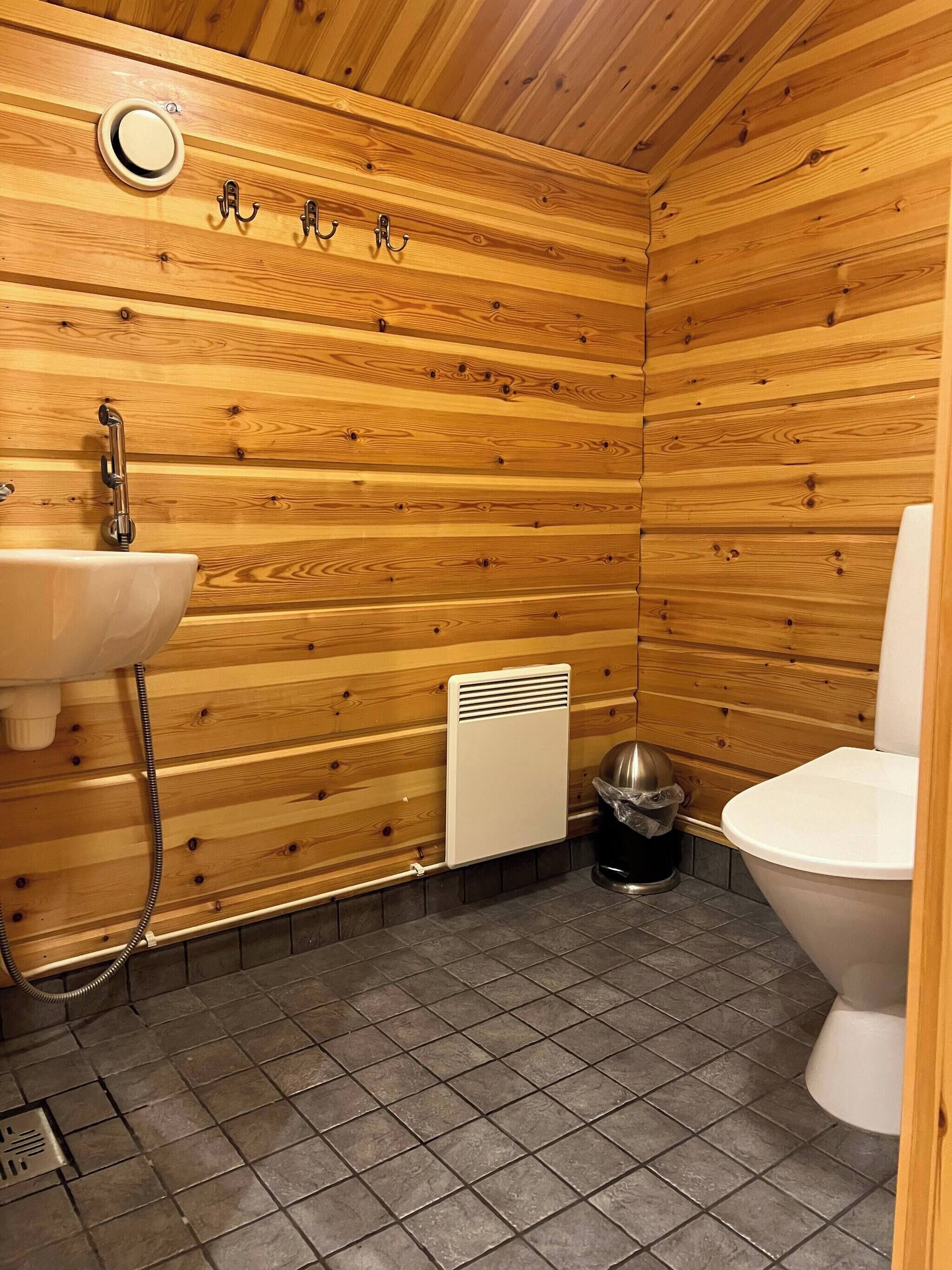 Un baño con paneles de madera, un lavabo, un inodoro y un calentador.