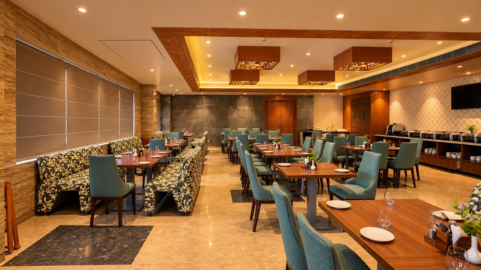 A restaurant with multiple dining tables and chairs, a bar area, and a seating section with patterned cushions.