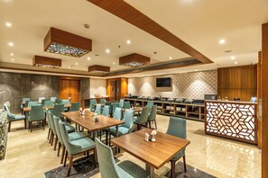 A hotel dining area with multiple tables and chairs, a buffet setup, and a decorative partition. - Royal Aravali Udaipur (Udaipur)