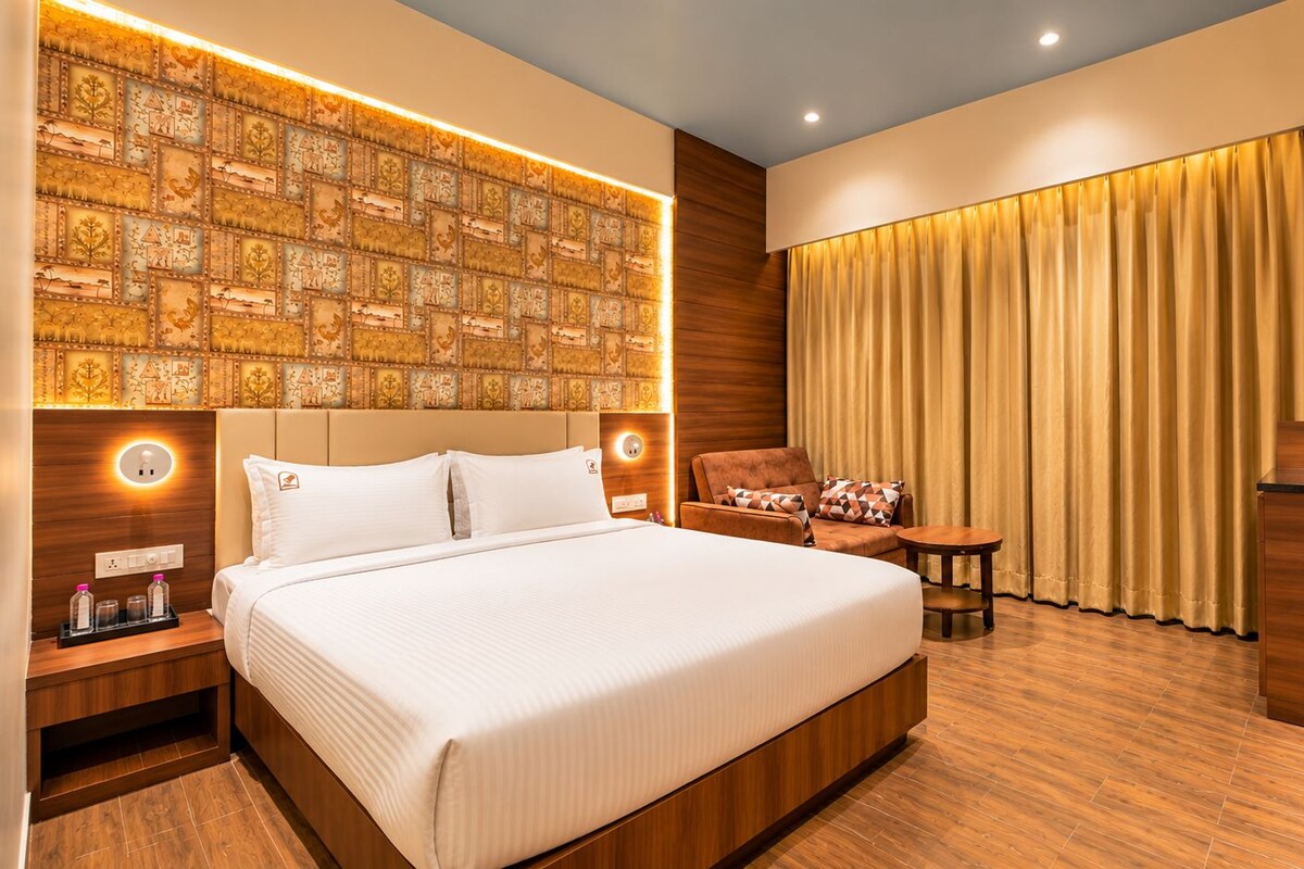 A hotel room with a large bed, a sofa, a small table, and a TV.