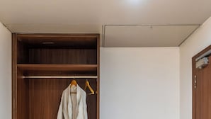 A walk-in closet with wooden shelving, a hanging robe, and a bench. - Royal Aravali Udaipur (Udaipur)