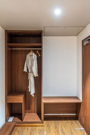 A walk-in closet with wooden shelving, a hanging robe, and a bench. - Royal Aravali Udaipur (Udaipur)