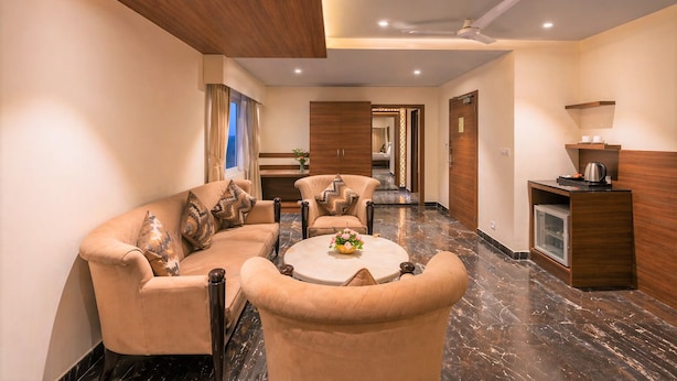A hotel lobby with a sofa set, a coffee table, a reception desk, and a hallway leading to other rooms. - Royal Aravali Udaipur (Udaipur)