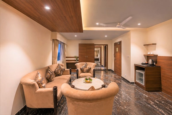 A hotel lobby with a sofa set, a coffee table, a reception desk, and a hallway leading to other rooms. - Royal Aravali Udaipur (Udaipur)