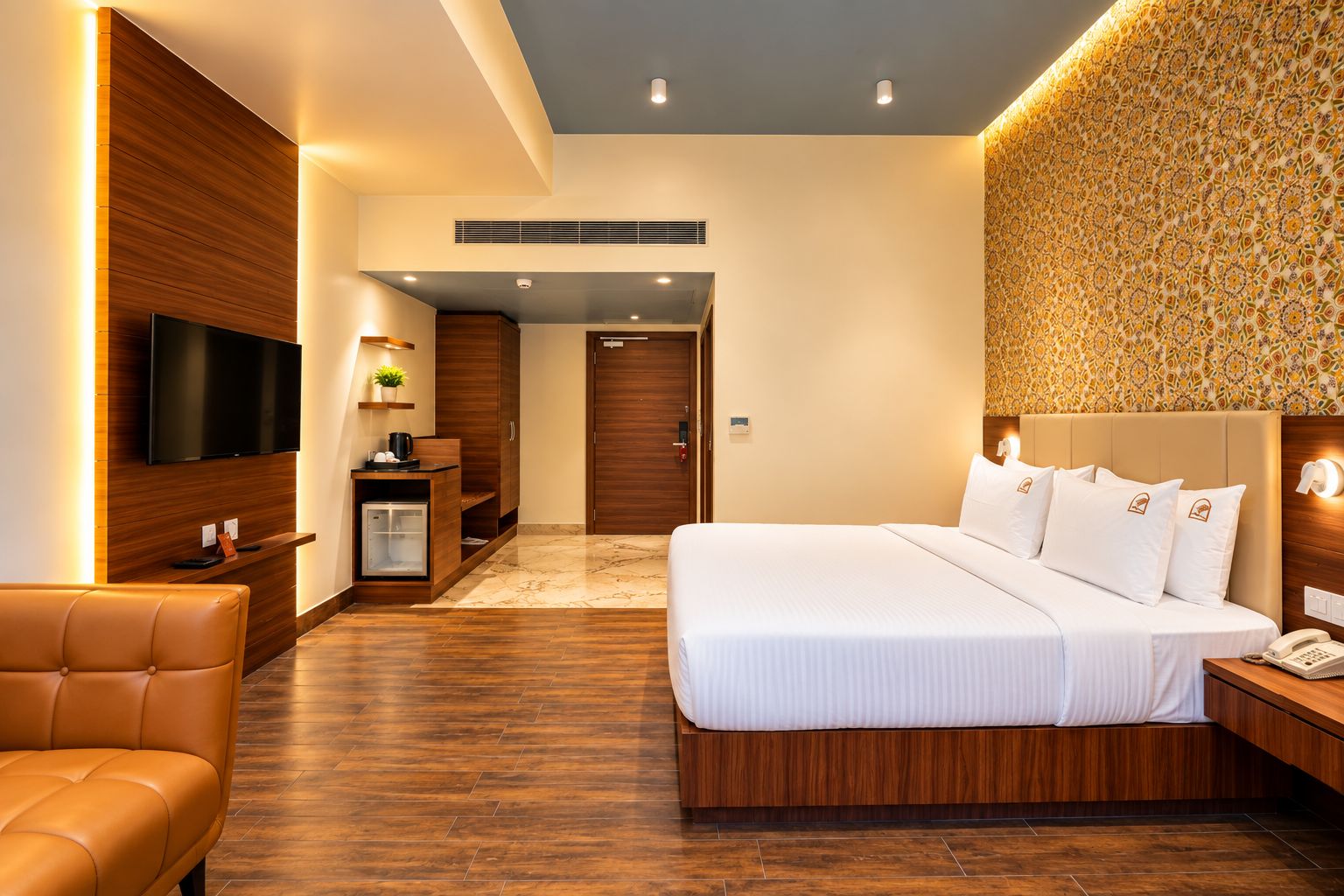 A modern hotel room with a large bed, a television, a desk, and a sofa.