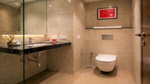 A modern bathroom with a glass-enclosed shower, a white toilet, and a vanity with a black countertop. - Royal Aravali Udaipur (Udaipur)