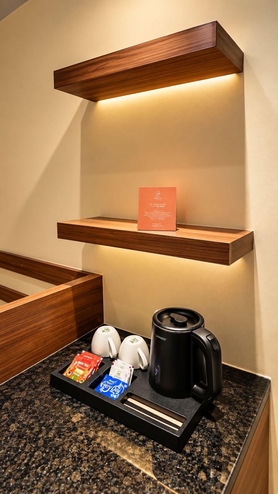 A hotel room with a coffee station, including a coffee maker, tea bags, and a sign.