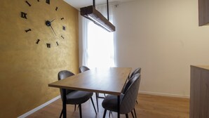 A dining area with a wooden table, four chairs, a wall clock, and a hanging light fixture. - Modern 2BR Top Floor Apartment + Free Parking (Pula)