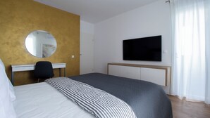 A bedroom with a bed, a desk, a chair, a television, and a mirror. - Modern 2BR Top Floor Apartment + Free Parking (Pula)