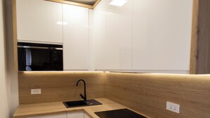 A modern kitchen with white cabinets, a black sink, and wooden countertops. - Modern 2BR Top Floor Apartment + Free Parking (Pula)