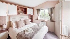 Ein Schlafzimmer mit einem Bett, Nachttischen, einem Fenster mit Vorhängen und einem Kleiderschrank.