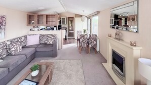 Ein Wohnzimmer mit einer Couch, Couchtisch, Kamin und einem Essbereich mit Stühlen und Tisch.