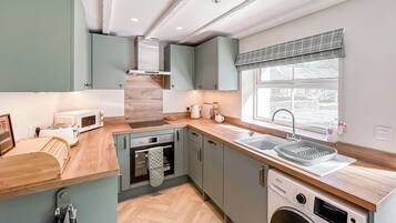 Una cocina compacta con horno integrado, microondas y lavavajillas, encimeras de madera y una ventana con vistas.