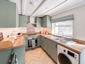 Una cocina compacta con horno integrado, microondas y lavavajillas, encimeras de madera y una ventana con vistas.