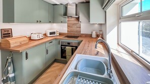 A compact kitchen with a sink, a toaster, a microwave, and wooden countertops. - 2 bedroom accommodation in Church Hill, Laxey (Church Hill, Laxey)
