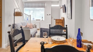 A dining area with a wooden table, chairs, and a view of the living room.