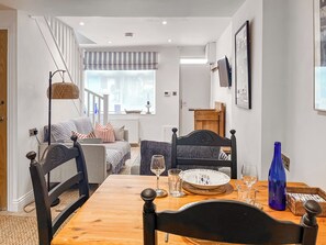 A dining area with a wooden table, chairs, and a view of the living room.