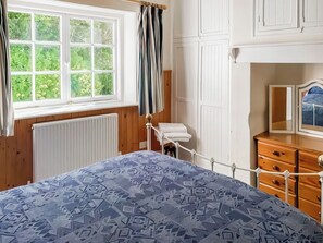 A bedroom with a bed, a dresser, a mirror, and a window with curtains. - 2 bedroom accommodation in Mullion (Mullion)