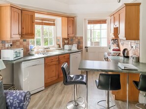 A kitchen with wooden cabinets, a microwave, a toaster, and a sink. - 2 bedroom accommodation in Mullion (Mullion)