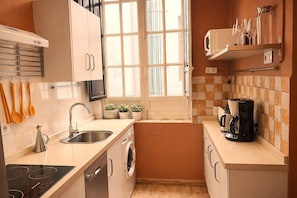 Cocina compacta con lavavajillas integrado, cocina y cafetera.
