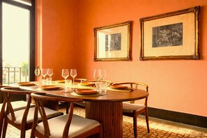 Un comedor con una mesa redonda preparada para seis personas, sillas y dos cuadros en la pared.