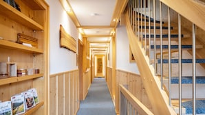 Interior de madera con una escalera, estanterías y piso alfombrado.