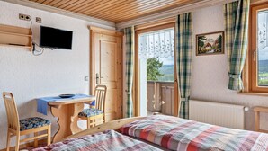 Una habitación con dos camas, un escritorio, una silla, un televisor y una ventana con cortinas.