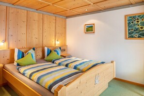 A double bed with striped bedding, wooden headboard, two bedside tables, and a painting on the wall.
