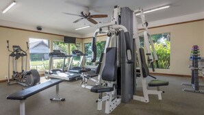 Un gimnasio con cintas de correr, un banco para press de pesas y máquinas de pesas.