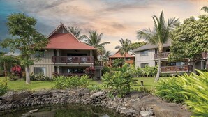 Un resort con edificios de varios pisos, un muro de contención de piedra y un pequeño estanque.