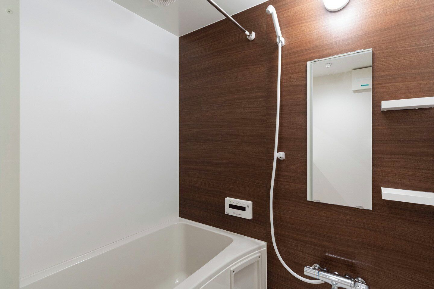 Un bagno con una vasca da bagno bianca, una parete in legno, uno specchio e un soffione.