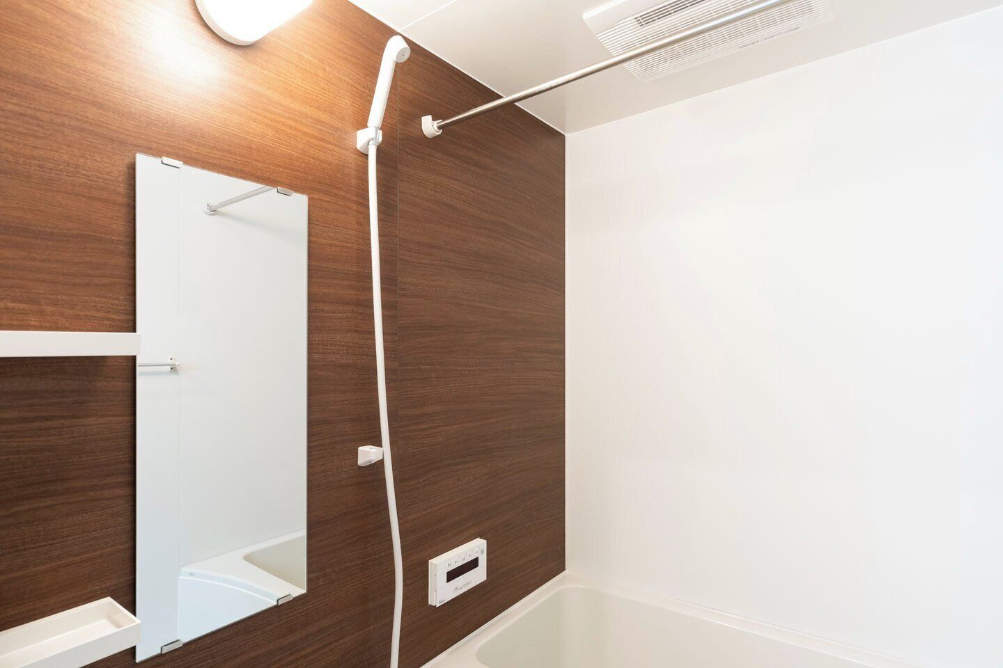 Ein Badezimmer mit Holzwand, Spiegel, Dusche und weißem Waschbecken.