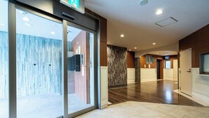 Ein Hotelkorridor mit Glastür, Holzwand, Fliesenboden und einem Fernsehbildschirm an der Wand.