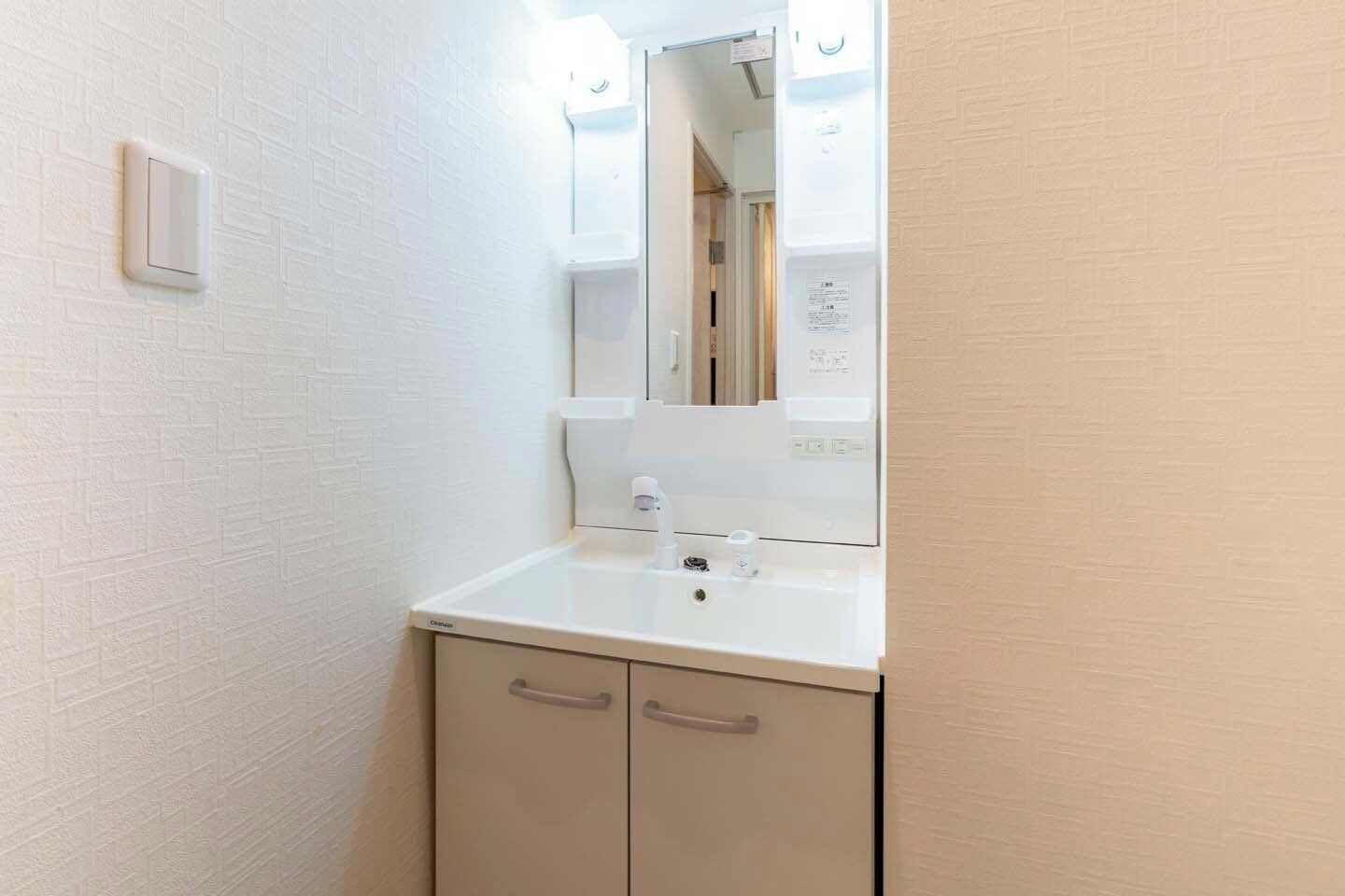 A bathroom with a white sink, mirror, and two cabinets.