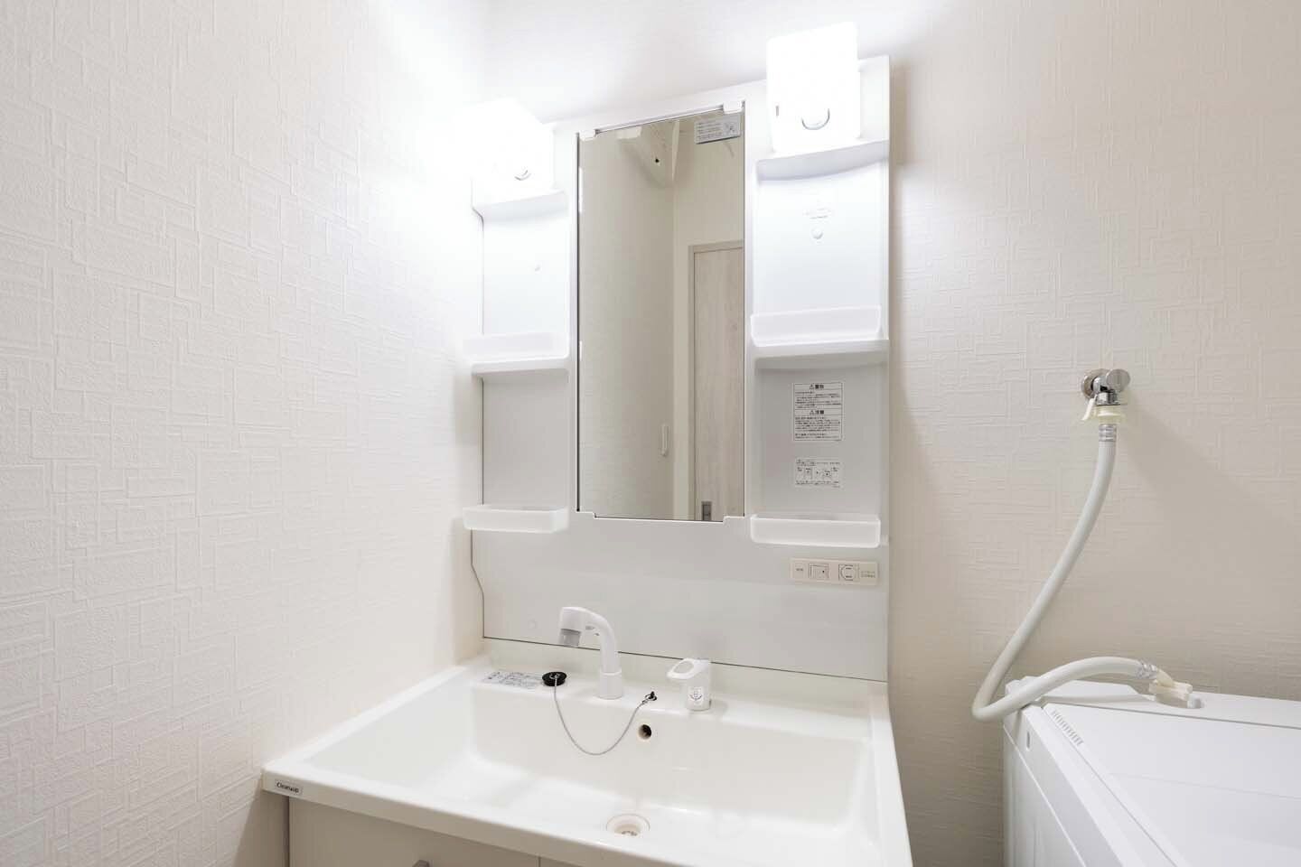 A bathroom with a white sink, a mirror, and a shower area.