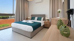 Una habitación de hotel moderna con una cama grande, una mesita de noche de madera, un escritorio y vistas al exterior.