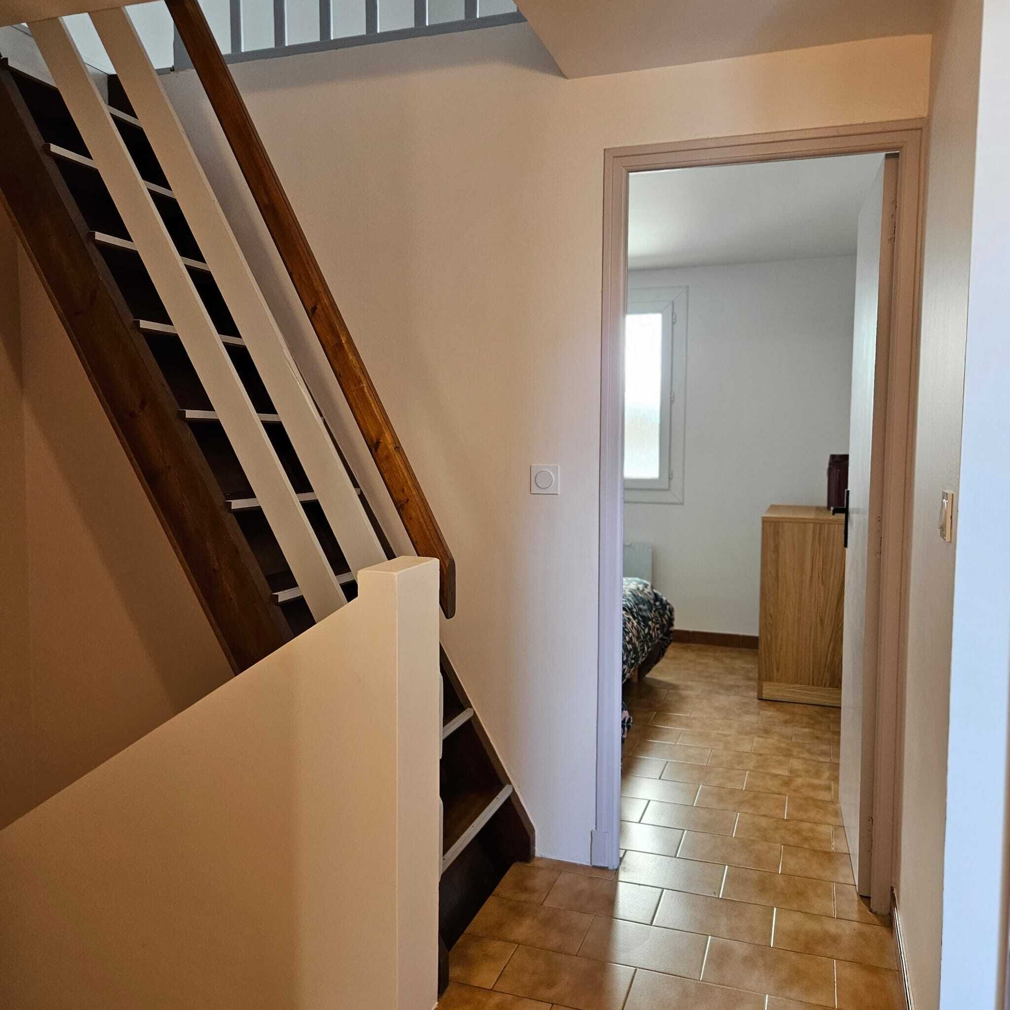 A staircase leading to a room with a bed and a wooden cabinet.