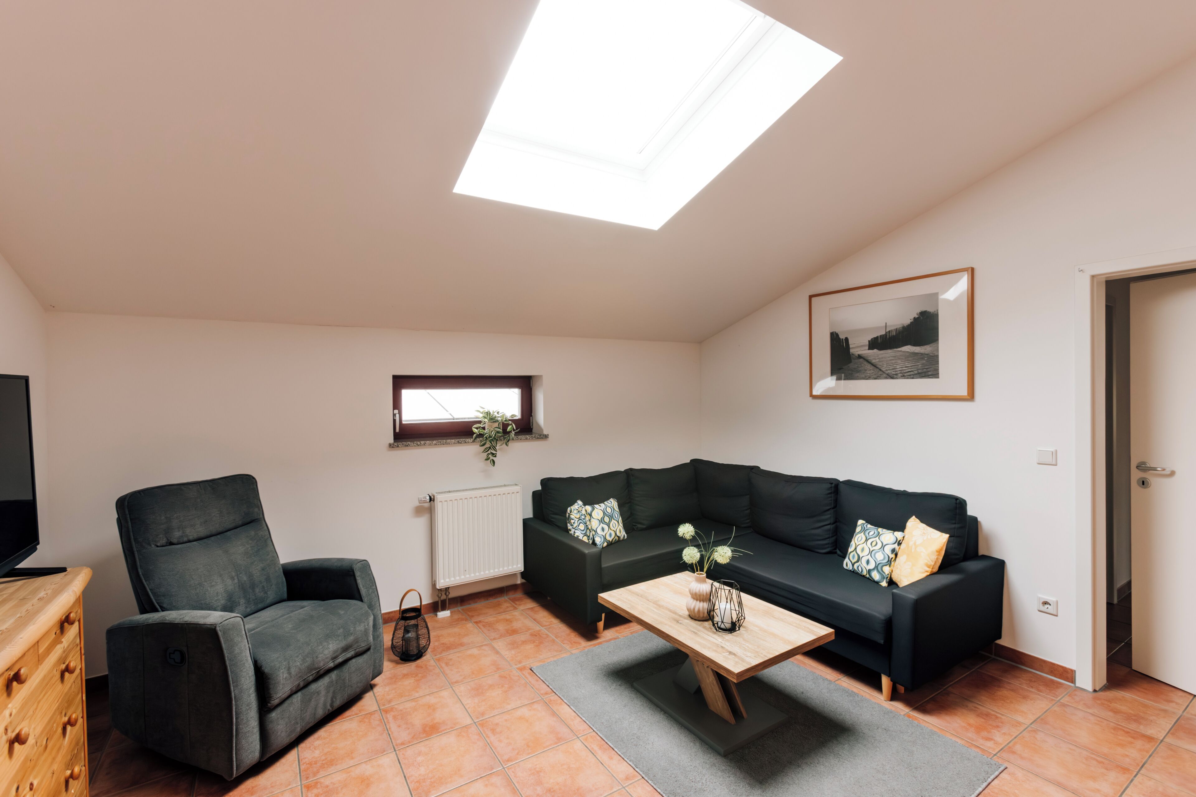 Ein Wohnzimmer mit Sofa, Sesseln, Couchtisch und einem Oberlicht.