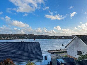 A coastal view with houses, a body of water, and a distant hill. - 4 bedroom accommodation in North Connel (North Connel)