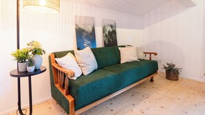 Een knus vertrek met een groene bank, een vloerlamp en een kleine tafel met planten.
