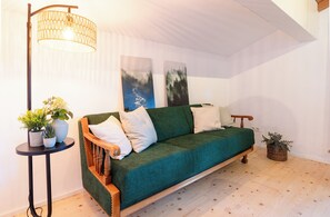 A cozy room with a green sofa, a floor lamp, and a small table with plants.