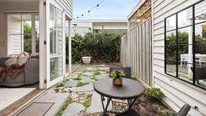 A patio with a sofa, a round table, and a potted plant. - Galatea Residence | Two Minutes to Beach and Town (Williamstown)