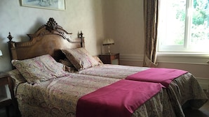 Un lit double avec une couvre-lit à motifs floraux et un plaid rouge.