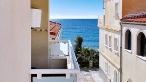 Eine schmale Straße mit einem Balkon mit Blick auf das klare, blaue Meer.