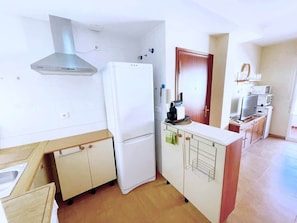 A compact kitchen with a built-in refrigerator, a microwave, and a stove. - Comeback Brisa Serena (Rubite)