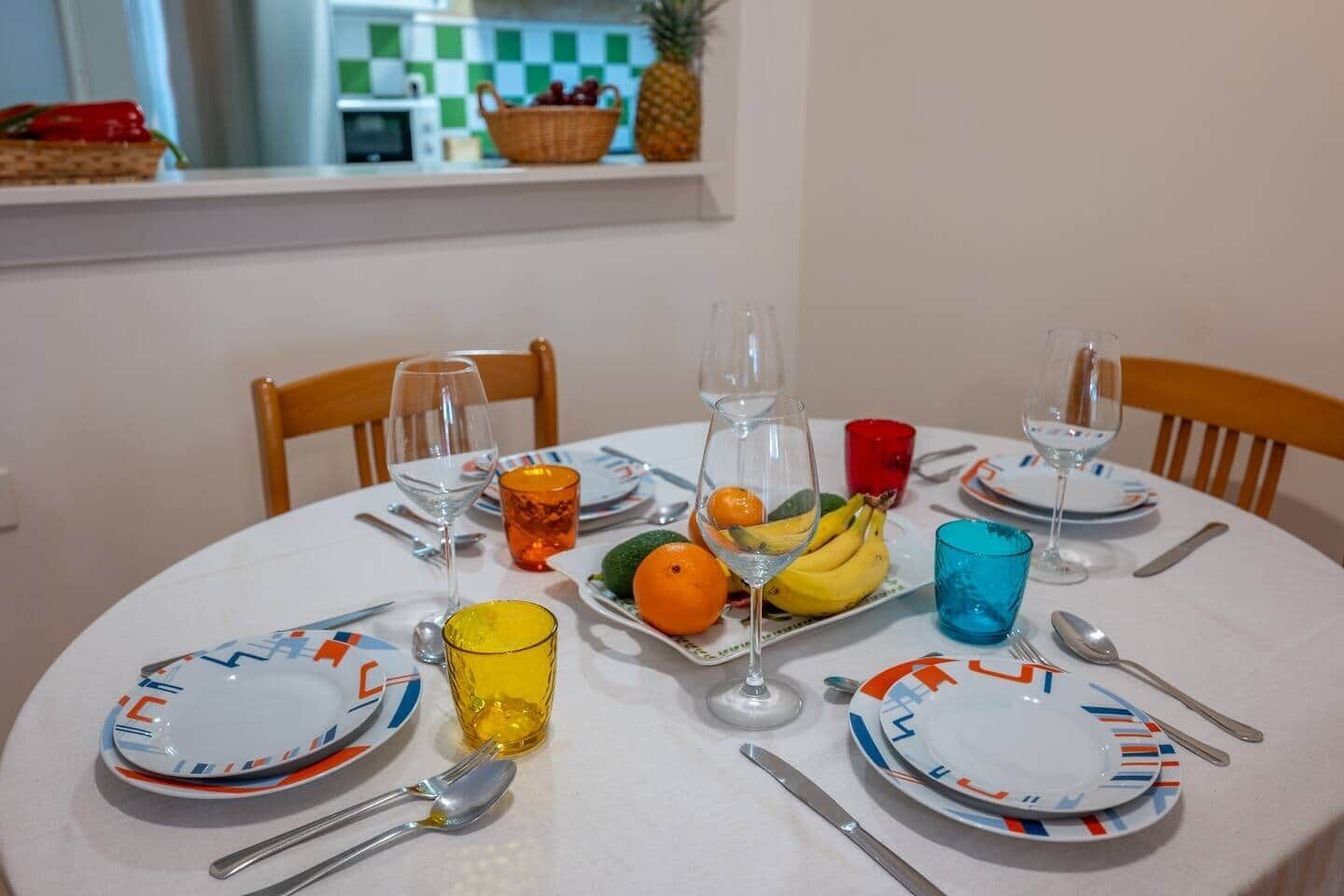 A dining table set with plates, glasses, cutlery, and fruit.