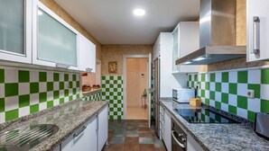 Eine Küche mit Schachbrettfliesen in Grün und Weiß, Granit Arbeitsplatten und weißen Schränken.